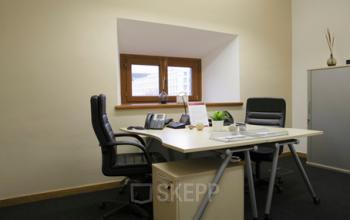 Bright office space rental at Kohlmarkt 8-10, 1010 Vienna with modern desk, ergonomic chairs, and storage cabinet.