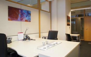 Modern office space rental at Kohlmarkt 8-10, 1010 Vienna, with a well-organized desk, comfortable chairs, and vibrant art.