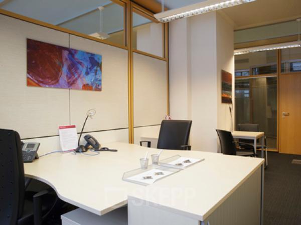 Modern office space rental at Kohlmarkt 8-10, 1010 Vienna, with a well-organized desk, comfortable chairs, and vibrant art.