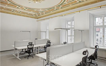 Elegante Bürofläche mieten in 1010 Wien mit dekorativer Decke und modernen Arbeitsplätzen, ideal für Kreativteams.