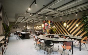 Modern office space rental at Nordbahnstraße 47, 1020 Vienna Leopoldstadt, with a stylish interior, communal work tables, and vibrant decor.