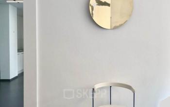 Bright office space rental at Mittersteig 10, 1050 Vienna Margareten featuring a minimalist white chair and circular mirror on a clean wall.