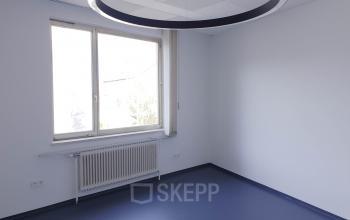 Modern and bright office space rental at Mittersteig 10 in 1050 Vienna Margareten with large windows and a unique circular lighting fixture.