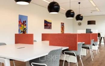 Helles Büro mit modernen Möbeln und einem großen Tisch, ideal zum Büro mieten. Kunstwerke an den Wänden ergänzen die Atmosphäre.