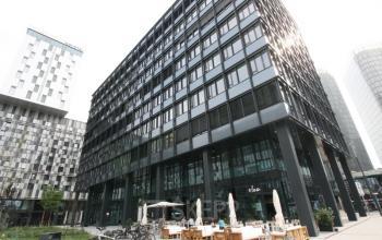 Bürogebäude Am Belvedere 8, 1100 Wien (Favoriten), Wien, mit Menschen, die in einem belebten Außenbereich sitzen.