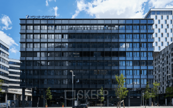 Modernes Bürogebäude zur Miete in Am Belvedere 8, 1100 Wien, Favoriten, mit verglaster Fassade und Umgebungsarchitektur im Hintergrund.