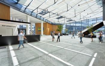 Spacious office space rental at Am Euro Platz 2, 1120 Vienna (Meidling) with people engaging in business activities in a modern, well-lit atrium lobby.