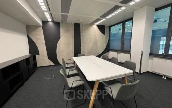 Modern office space rental at Am Euro Platz 2, 1120 Vienna Meidling, with a sleek white table, comfortable chairs, and stylish geometric wall design.