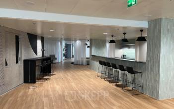 Modern office space rental at Am Euro Platz 2, 1120 Vienna (Meidling) with a well-appointed lounge area including a bar and seating.