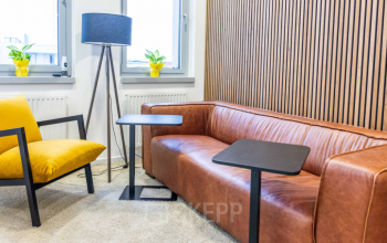 Trendy lounge area in Wagenseilgasse 14 office space rental with cozy brown sofa, stylish armchair, and modern decor inviting for a creative break in 1120 Vienna (Meidling).