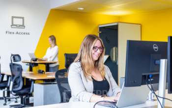Sunny office space rental at Wagenseilgasse 14, 1120 Vienna Meidling, with smiling professionals working at ergonomic stations.