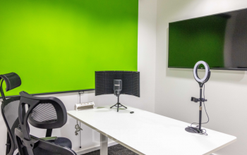 Modern Wagenseilgasse 14 office space rental in 1120 Vienna Meidling with vibrant green accent wall, equipped with desk, chair, and multimedia setup.
