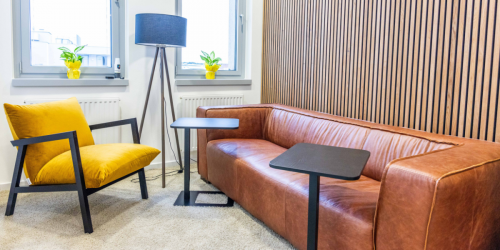 Trendy lounge area in Wagenseilgasse 14 office space rental with cozy brown sofa, stylish armchair, and modern decor inviting for a creative break in 1120 Vienna (Meidling).