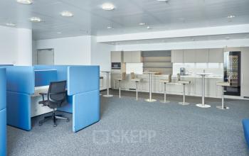 Modern office space at Floridsdorfer Hauptstraße 1, 1210 Vienna with blue workstations and a kitchen area for office space rental.