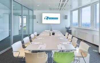 Modern conference room for office space rental at Floridsdorfer Hauptstraße 1, Vienna, featuring a large table and chairs, ample natural light and a screen.