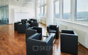 Modern, bright lounge area with black leather chairs and large windows at Floridsdorfer Hauptstraße 1, 1210 Vienna.