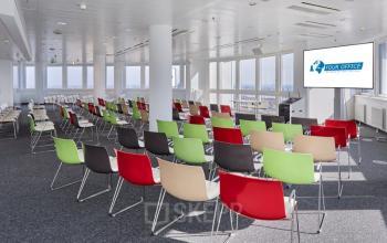 Wide office space rental with colorful chairs arranged in rows, large windows providing natural light at Floridsdorfer Hauptstraße 1, 1210 Vienna.