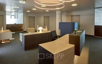 Modern office interior at Floridsdorfer Hauptstraße 1, 1210 Vienna with sleek furnishings, stylish lighting fixtures, and a reception desk area for office space rental.