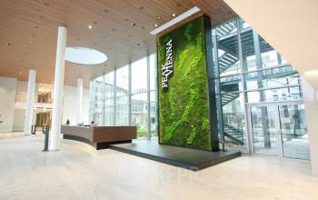 Modern reception area at Floridsdorfer Hauptstraße 1, 1210 Vienna, featuring a sleek desk and a large green vertical garden. Ideal office space rental in Floridsdorf.