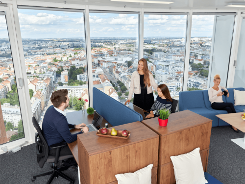 Helles Büro in der Floridsdorfer Hauptstraße 1, 1210 Wien, mit modernen Möbeln und beeindruckender Aussicht. Drei Personen arbeiten und diskutieren.