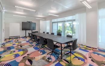 Moderner Konferenzraum mit langem Tisch und buntem Teppich in der Siemensstraße 89, ideal für büroraum mieten in Wien Floridsdorf.