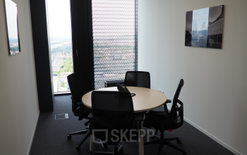 Modern office space rental at Donau-City-Straße 7, 1220 Vienna (Donaustadt) with a round table and chairs for meetings, floor-to-ceiling windows, and city view.