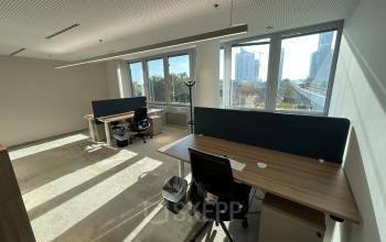 Spacious office at Wagramer Straße 19, 1220 Vienna, Donaustadt with large windows and modern furnishings, featuring desks and chairs. Ideal for office space rental with natural lighting and city views.