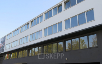 Modern office space rental at Kolbegasse 66, 1230 Vienna (Liesing), featuring a sleek exterior with expansive windows reflecting the sky.