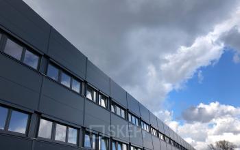 Sleek facade of office space rental at IZ NÖ Süd Straße 3, 2351 Vienna Neudorf under a dynamic sky.