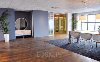 Spacious, modern office space with wooden flooring, a large meeting table, and contemporary furnishings at van Cleeffkade 15 in Aalsmeer, ideal for office space rental.