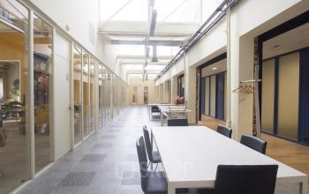 Bright interior office space with skylights and white tables, located at van Cleeffkade 15, Aalsmeer, available for office space rental.
