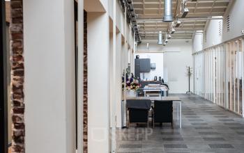 Interior of an office to rent at van Cleeffkade 15, Aalsmeer, with modern furnishings, shared workspace, and high ceilings.