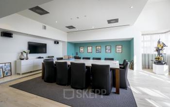 Modern conference room at van Cleeffkade 15, Aalsmeer, with a large table, black chairs, and wall art, available for office space rental.