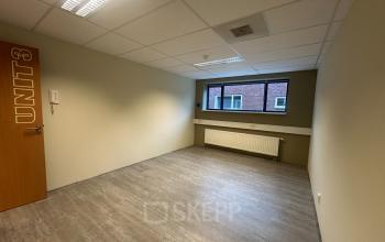 Empty office space at Hollandse Kade 38, Abcoude, featuring a neutral-toned interior with large window and overhead lighting, available for rent. Ideal for setting up your next office to rent.