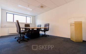 Office space rental at Hollandse Kade 38, Abcoude: a modest conference room with a table and four chairs, featuring ample natural light from a large window.