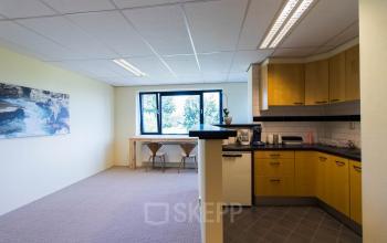 Bright office space with simple kitchen amenities and seating area at Hollandse Kade 38 in Abcoude, ideal for office space rental with natural light and a cozy atmosphere.