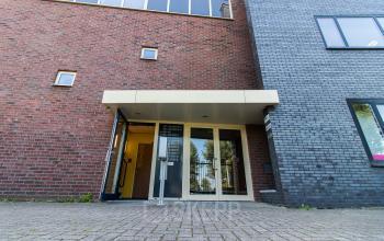 Entrance of an office building at Hollandse Kade 38, Abcoude, showcasing modern glass doors and brick exterior, perfect for attracting business professionals seeking office space rental.