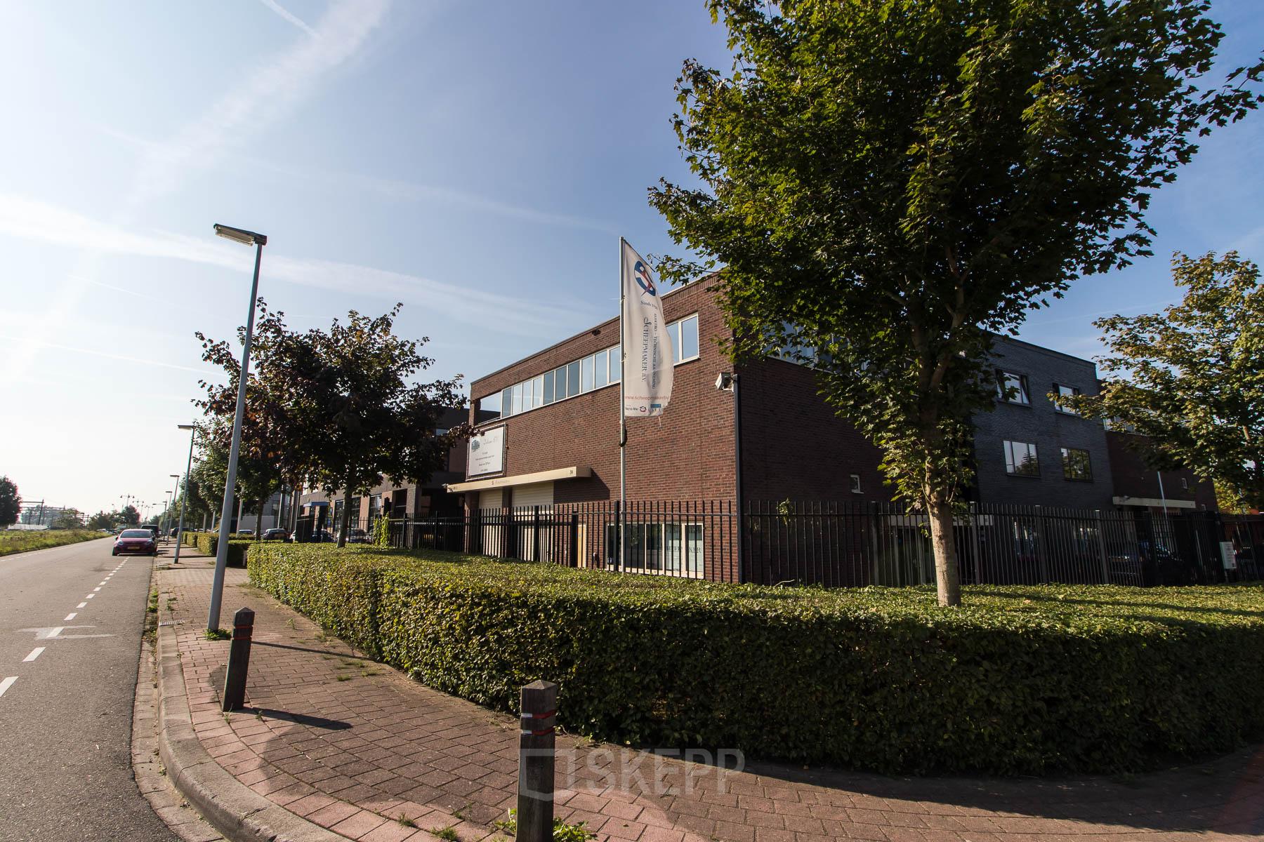 Exterior view of the office building at Hollandse Kade 38, Abcoude. The modern brick facade and lush greenery surround the perimeter, offering a welcoming glimpse for those interested in office space rental.
