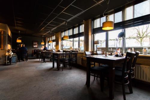 Office space rental at Bedrijvenpark Twente 305 in Almelo, featuring a furnished area with tables and chairs, large windows, and pendant lighting.