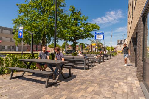 Outdoor seating area at Brugstraat 9-13, Almelo, featuring people engaged in casual business conversations. Ideal spot for a break or informal meetings in this office to rent.