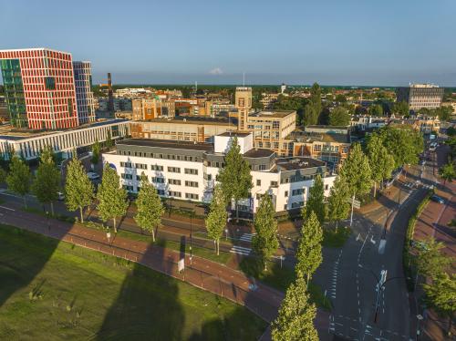 Aerial view of an office building at Egbert Gorterstraat 2-14, Almelo, surrounded by trees with roads running alongside. The space offers opportunities for office space rental in a bustling business district.