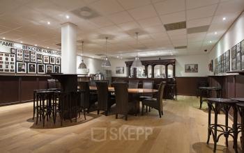 Spacious furnished lounge with wooden floors, large tables and chairs, located in the office at Twentepoort Oost 61, Almelo.