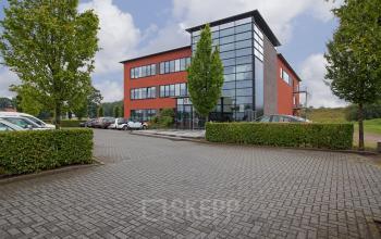 Modern office space rental at Twentepoort Oost 61 in Almelo with a red brick building facade and parking in front.