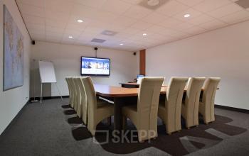 Conference room at Twentepoort Oost 61, Almelo, with a large table and chairs, a whiteboard, and a wall-mounted screen, ideal for office space rental.