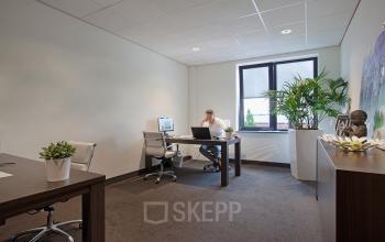 Office space rental at Twentepoort Oost 61, Almelo, featuring desks, chairs, plants, and a person working at a computer.