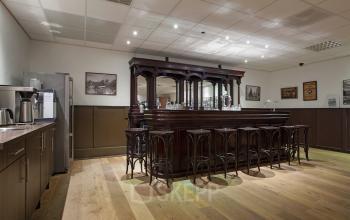 Cozy office pantry at Twentepoort Oost 61 in Almelo featuring a large wooden bar counter, high stools, and kitchen facilities.