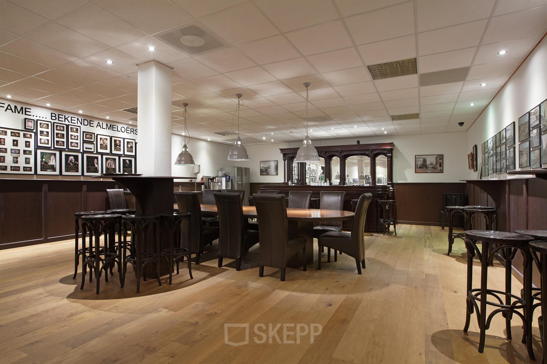 Spacious furnished lounge with wooden floors, large tables and chairs, located in the office at Twentepoort Oost 61, Almelo.