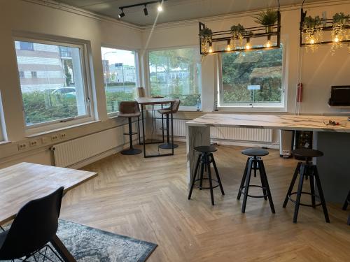 Bright office space at Kabelstraat 5, Almere Poort, featuring large windows, wooden flooring, and modern seating. Ideal for office space rental.