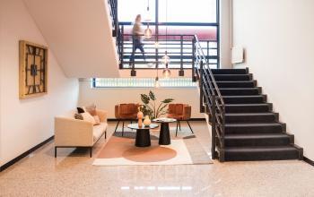 Modern office entrance with stylish furnishings at Markerkant 1310, Almere Stad. Features a seating area, staircase, and contemporary decor, ideal for businesses seeking office space rental.