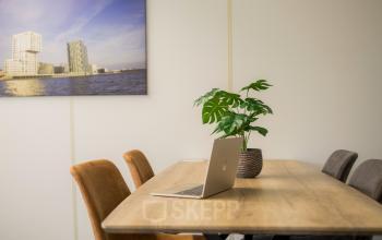 Modern office space at Markerkant 1310, Almere Stad with a wooden table, comfortable chairs, a laptop, and a plant.